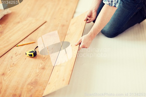 Image of close up of male hands intalling wood flooring