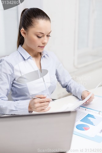 Image of businesswoman with laptop and charts in office