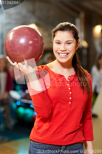 Image of happy young woman holding ball in bowling club