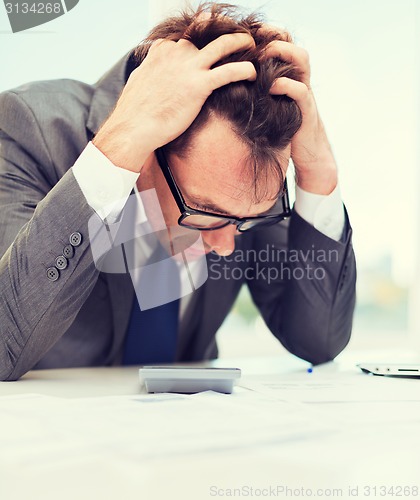 Image of businessman with papres, laptop and calculator