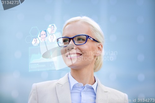 Image of young smiling businesswoman in eyeglasses outdoors