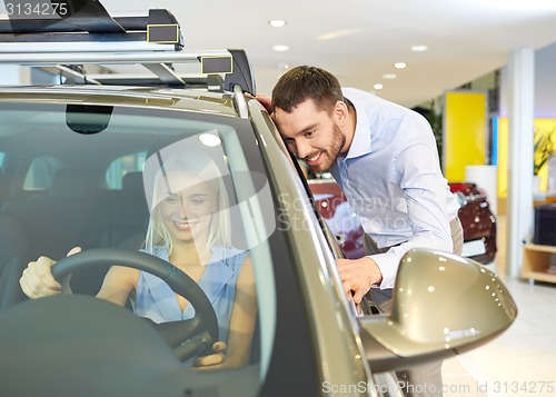 Image of happy couple buying car in auto show or salon