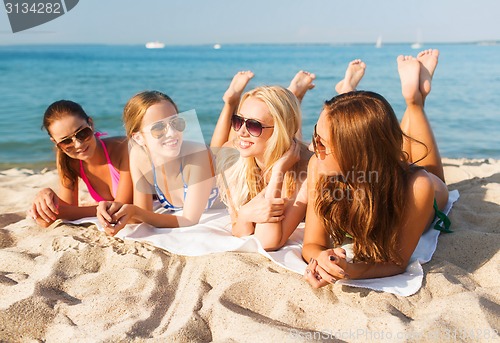 Image of group of smiling women in sunglasses on beach