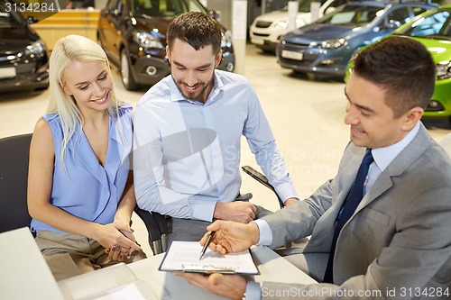 Image of happy couple with car dealer in auto show or salon