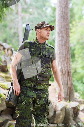 Image of young soldier or hunter with gun in forest