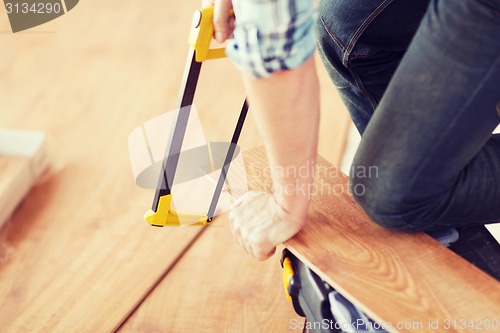 Image of close up of male hands cutting parquet floor board