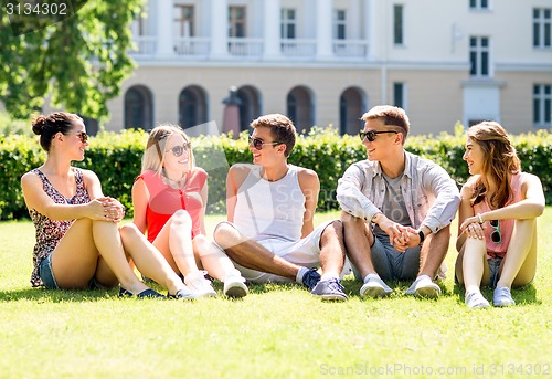 Image of group of smiling friends outdoors sitting on grass