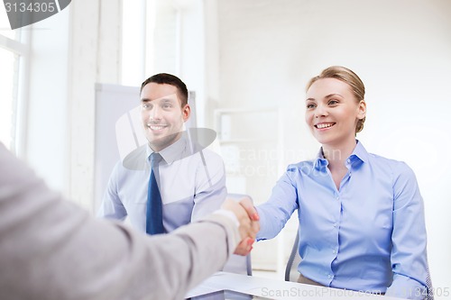 Image of smiling businesswoman making handshake in office