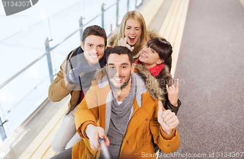 Image of happy friends taking selfie on skating rink