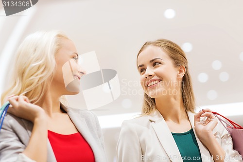 Image of happy young women with shopping bags in mall