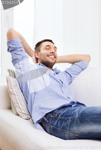 Image of smiling man relaxing on couch at home