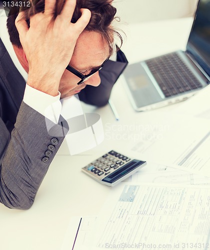 Image of businessman with papres, laptop and calculator