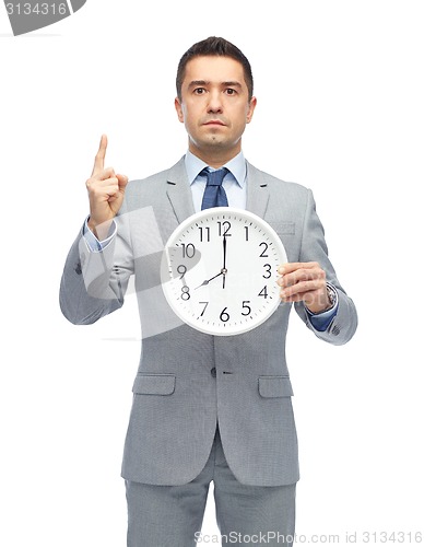 Image of businessman in suit holding clock with 8 o'clock