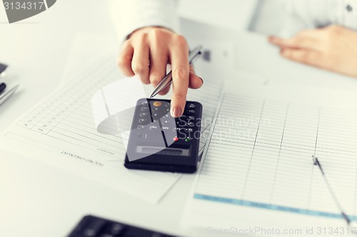 Image of woman hand with calculator and papers