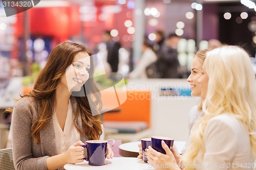 Image of smiling young women drinking coffee in mall 