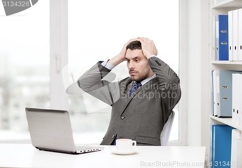 Image of busy businessman with laptop and coffee