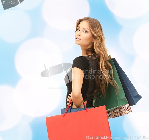 Image of young woman with shopping bags over blue lights