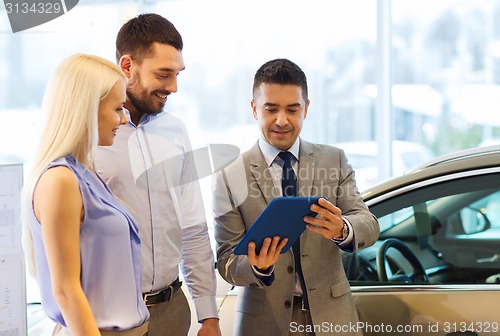 Image of happy couple with car dealer in auto show or salon