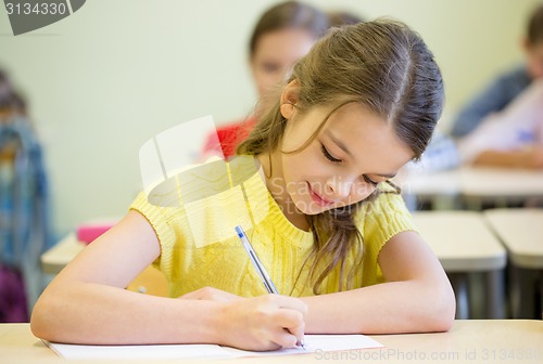 Image of group of school kids writing test in classroom