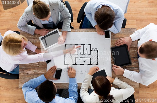 Image of business team with blueprint and gadgets