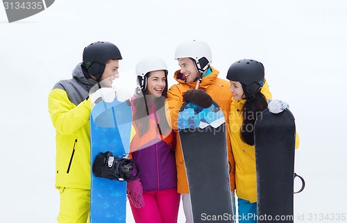 Image of happy friends in helmets with snowboards talking
