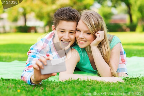 Image of smiling couple making selfie in park