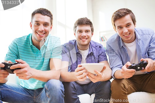 Image of smiling friends playing video games at home