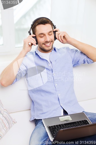 Image of smiling man with laptop and headphones at home