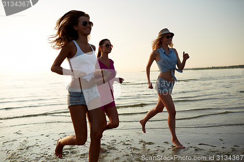 Image of group of smiling women running on beach