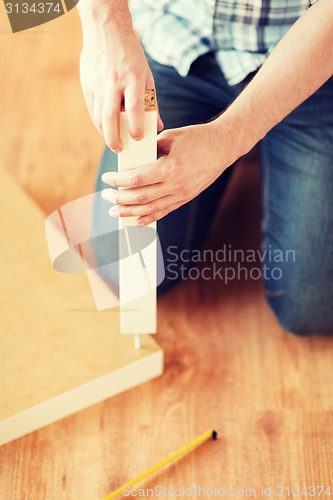 Image of close up of male hands assemblying legs to table