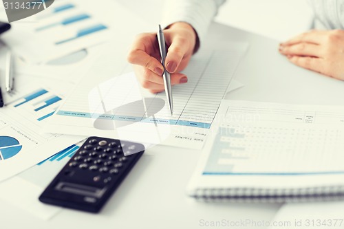 Image of woman hand with calculator and papers