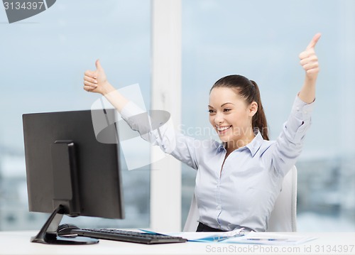 Image of woman with computer, papers showing thumbs up