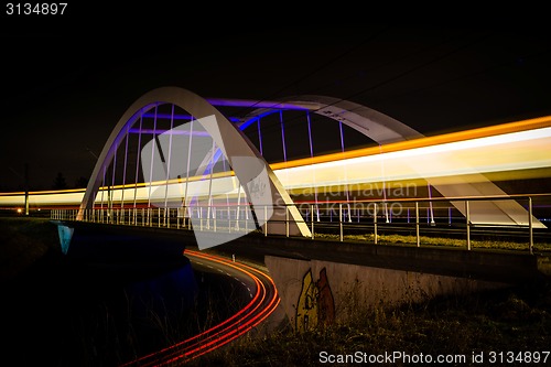 Image of Railway bridge with train and car lights  at night