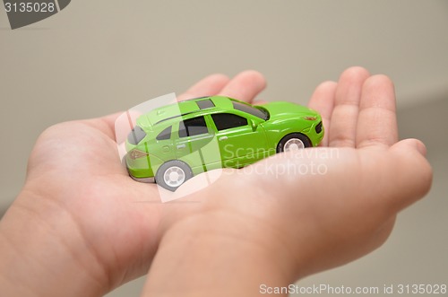 Image of Green toy car on a right hand
