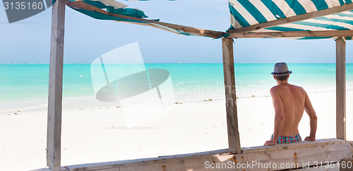 Image of Hipster man with hat on tropical sandy beach.