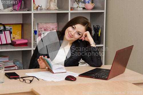 Image of employee with a smile, looking into frame before opening notepad