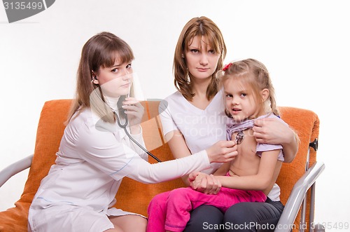 Image of Pediatrician listening stethoscope breast girl sitting on mothers hands