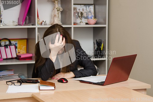 Image of Girl in the office clutching her head