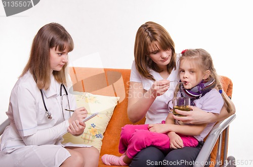 Image of Pediatrician prescribes treatment child whose mother gives to drink tea from a spoon