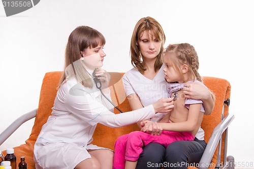 Image of Pediatrician checks breath stethoscope a little girl in the arms of mother