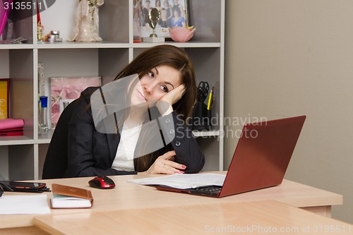 Image of girl in office looking wistfully into monitor