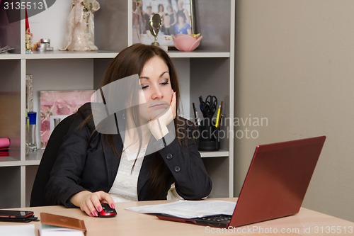 Image of The girl in office of a tired looking into computer