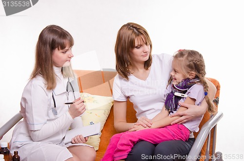 Image of Sick girl sitting on lap of mother and pediatrician inspection