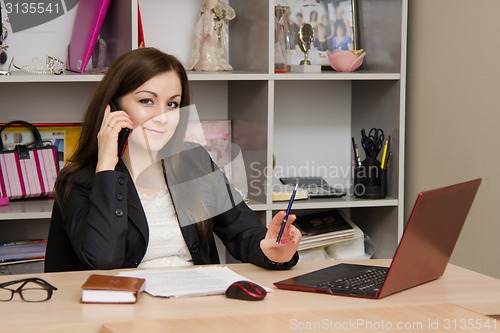 Image of employee of office is a telephone conversation at computer