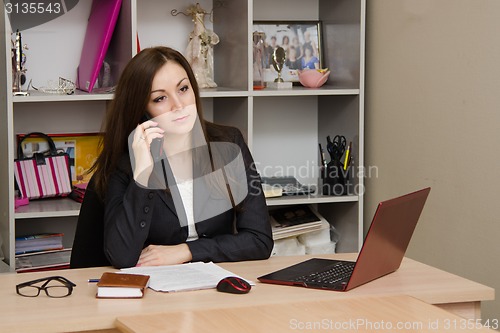 Image of Worried office employee sitting at desk with a phone