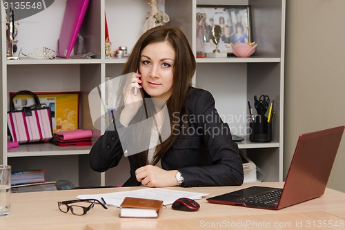 Image of Business woman at the office conducts a dialogue by phone