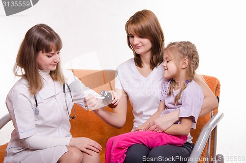 Image of Pediatrician pours medicine into a spoon, which holds mother of sick child