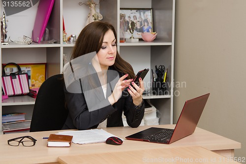 Image of Girl intently dials the number in office front of computer