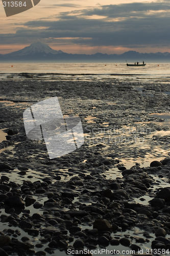 Image of Cook inlet low tide beach with fisherman boat and volcanoe in ba