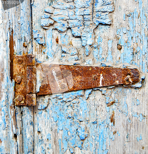 Image of rusty metal     nail dirty stripped paint in the blue wood door 